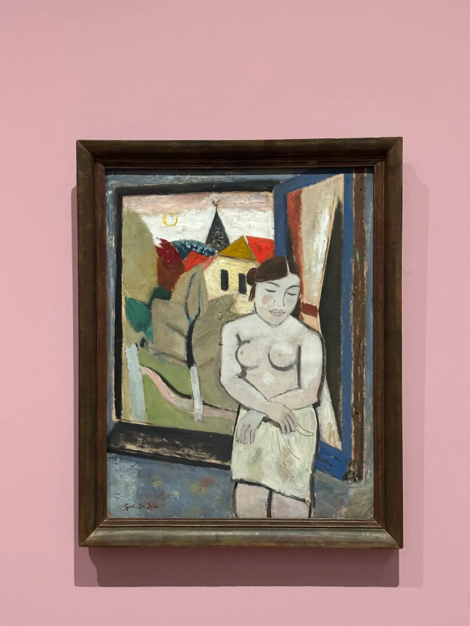 Schilderij van een naakte vrouw bij een open raam, met een dorp en kerk op de achtergrond, tentoongesteld tegen een zachtroze museumwand.