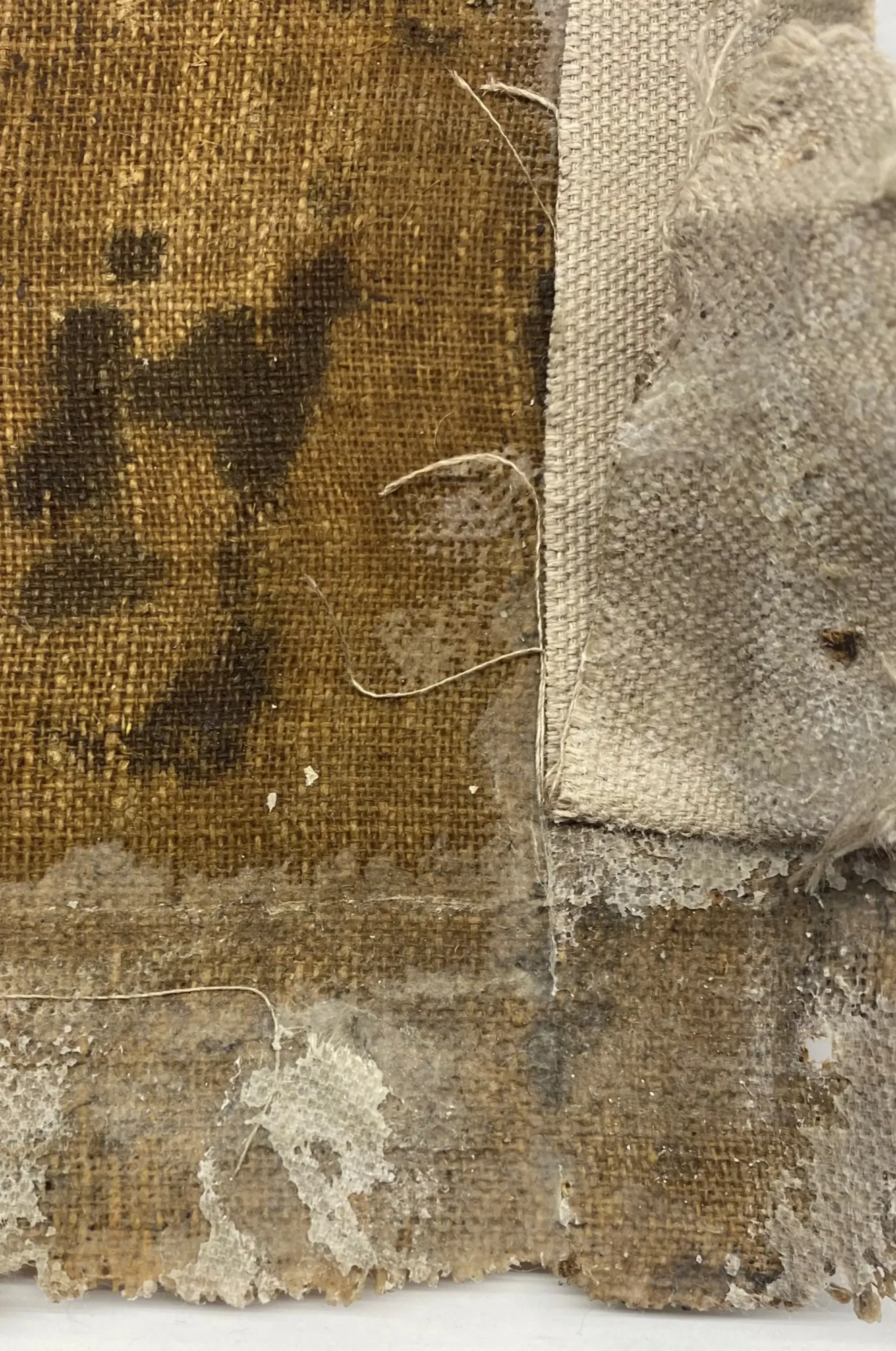 Detail van de achterzijde van het schilderij tijdens het verwijderen van de stripvoering, waarbij de oorspronkelijke doekrand zichtbaar wordt.
