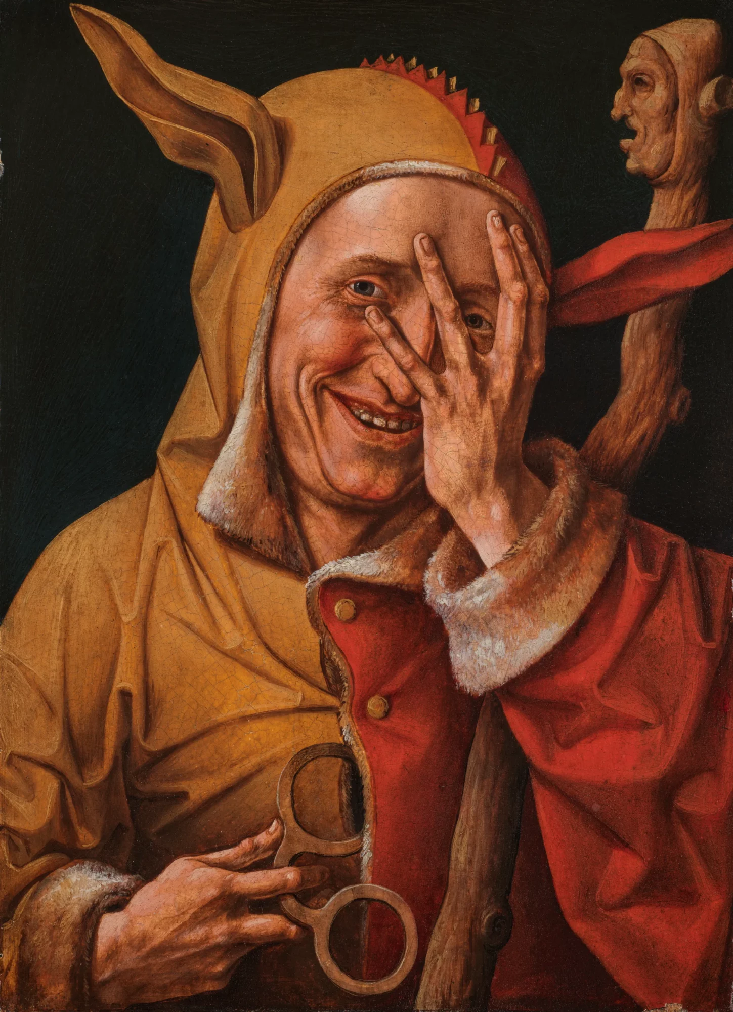Detail van een laatmiddeleeuwse nar die lachend met één hand zijn gezicht bedekt en een narrenkap draagt.