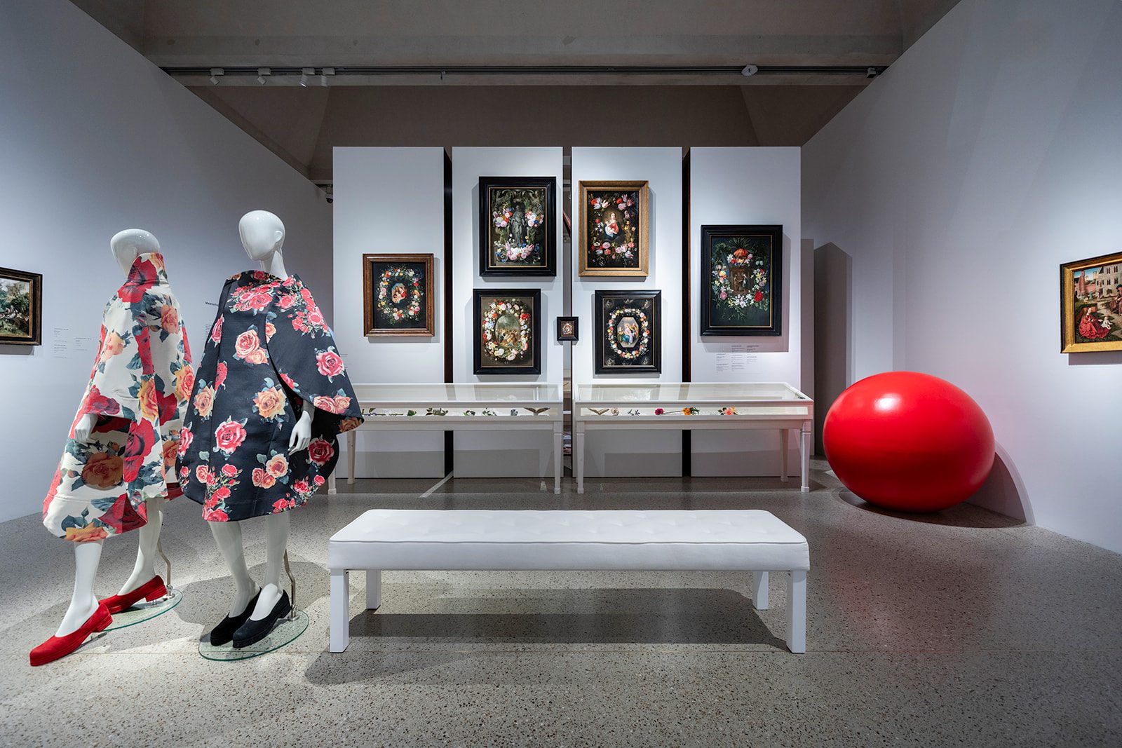 Two mannequins in floral fashion beside seventeenth-century flower still lifes in the Garden of Delights exhibition at Museum De Lakenhal.