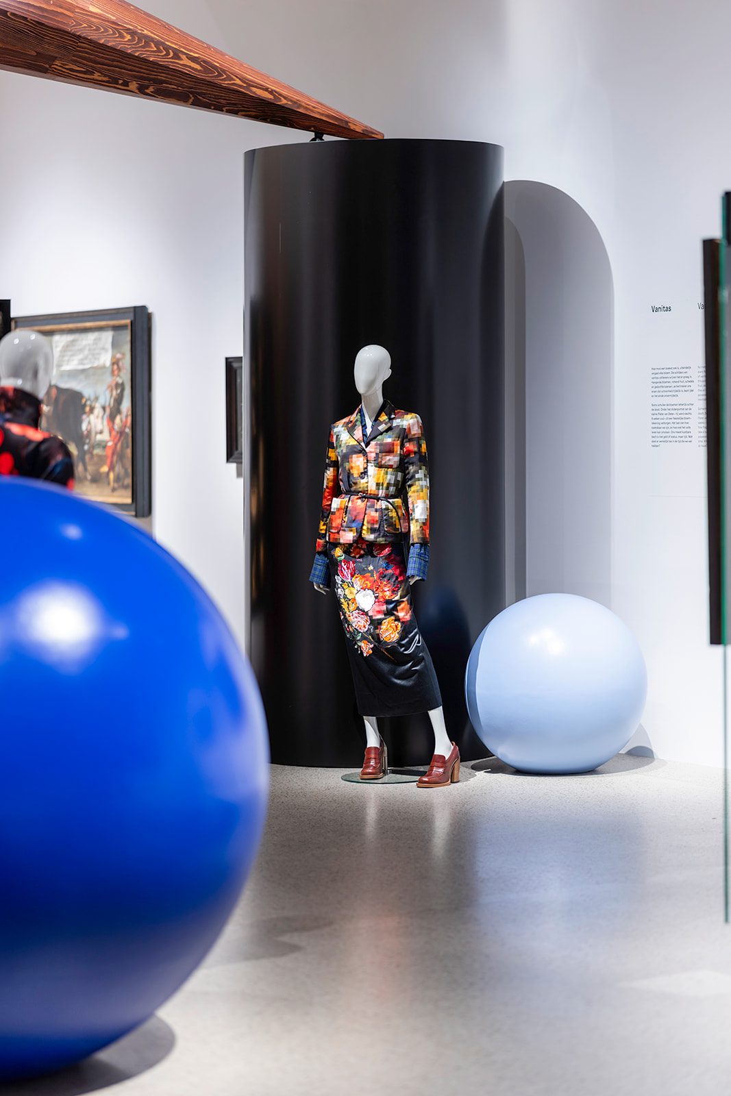Mannequin in a floral fashion creation among monumental blue spheres in the scenography of Garden of Delights at Museum De Lakenhal.