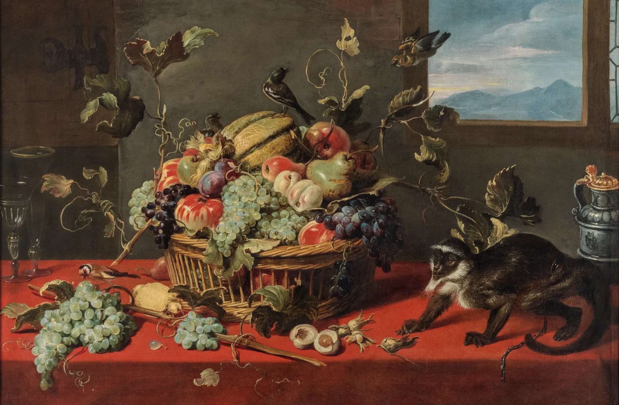 Schilderij van Frans Snijders met een rijkgevulde fruitmand op een rood tafelkleed, omringd door druiven, fruit, vogels en een aap.